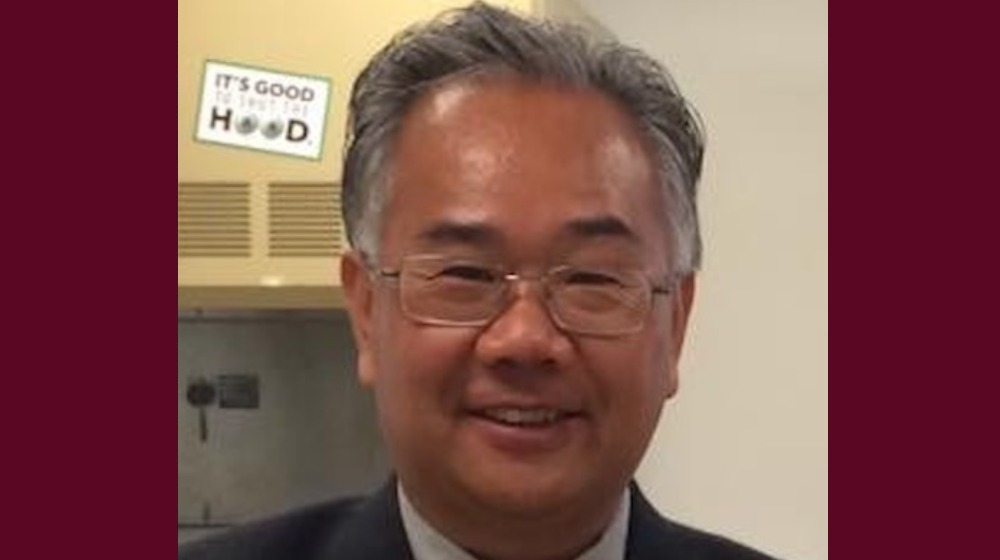 Smiling man wearing glasses in an indoor setting.